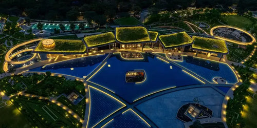 DLF THE CAMELLIAS luxury real estate property featuring illuminated modern architecture with rooftop gardens and expansive water features at night.